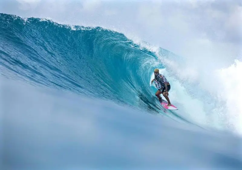 Un surfeur chevauche une vague puissante dans une eau turquoise.