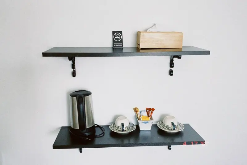 Une bouilloire et des accessoires pour le thé sont posés sur une étagère murale.