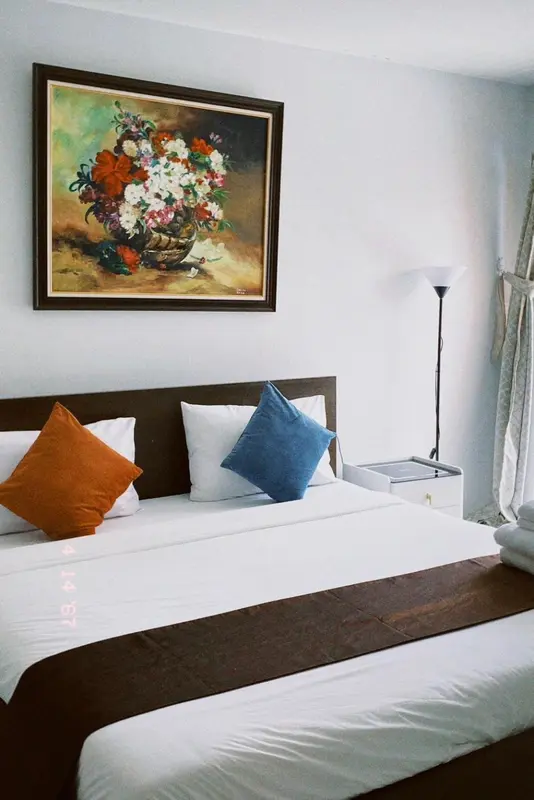 Un lit avec des oreillers et une peinture florale au mur.