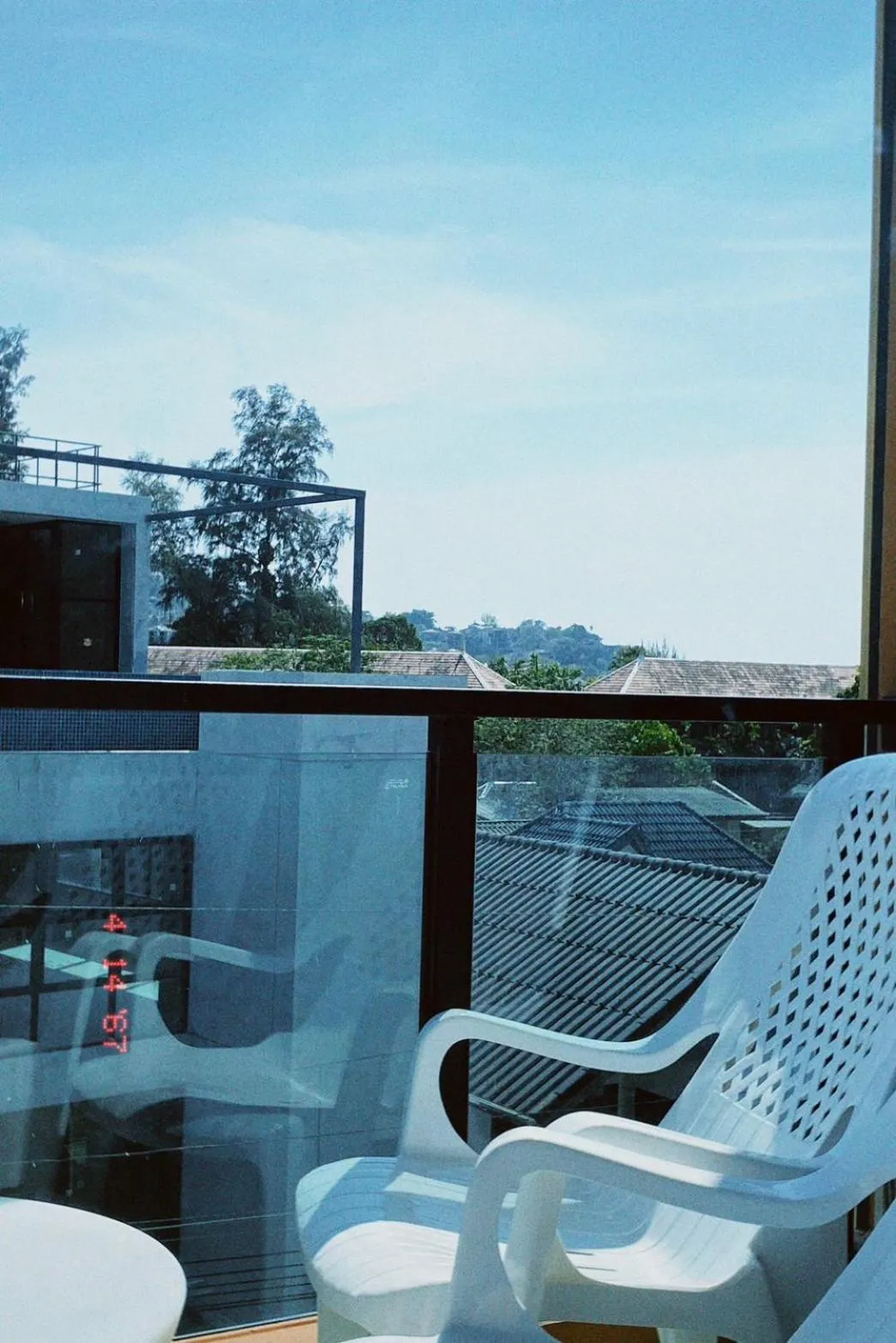 Terrasse ensoleillée avec mobilier blanc et vue sur la végétation.
