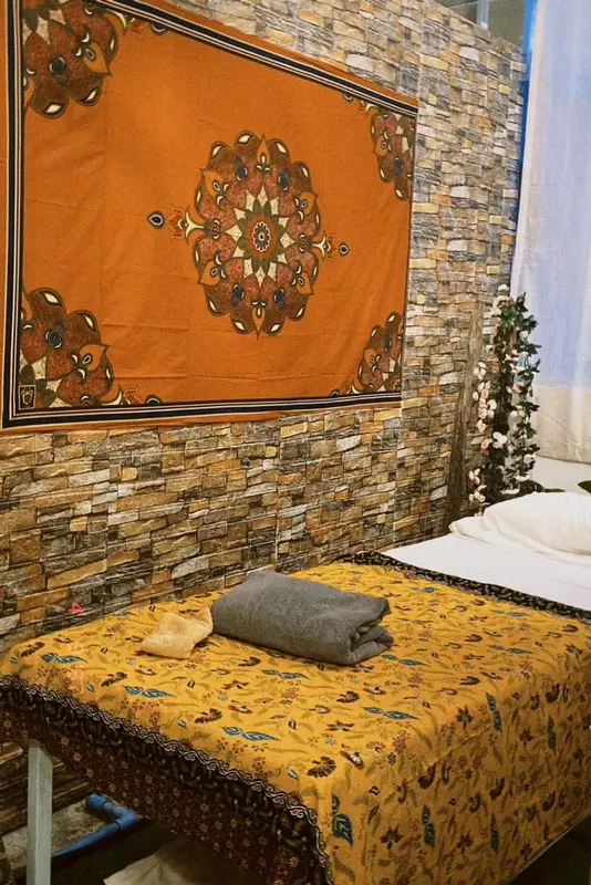 Un lit recouvert d'un couvre-lit floral se trouve contre un mur en pierre.