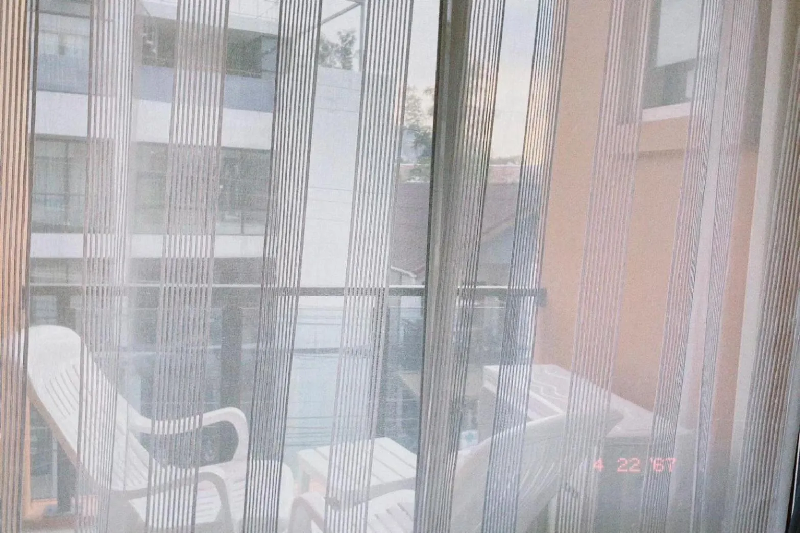 Vue sur une terrasse avec des fauteuils blancs et une piscine.