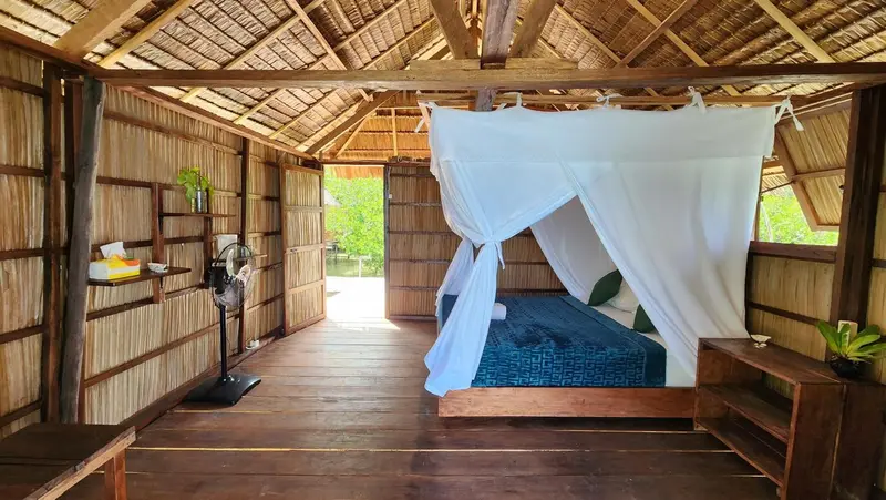 Une chambre rustique avec un lit à baldaquin et un sol en bois.