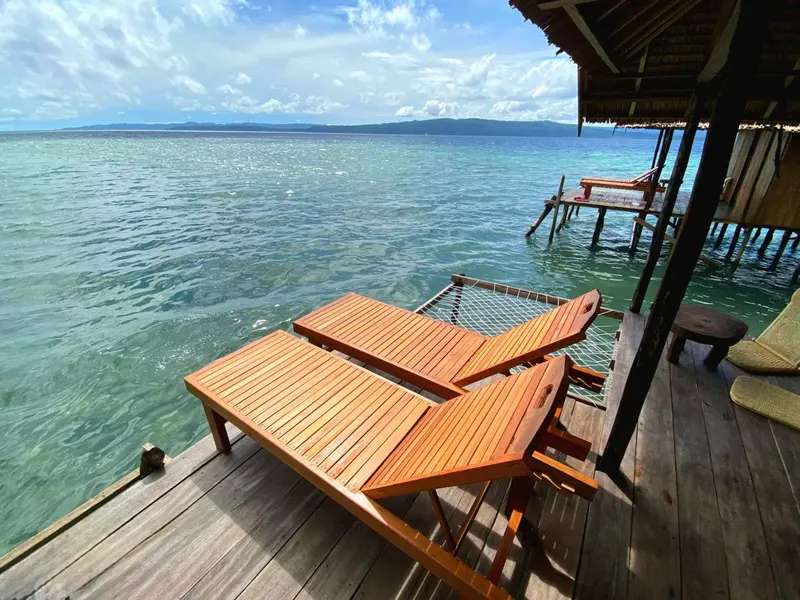 Terrasse en bois avec mobilier donnant sur une mer turquoise.
