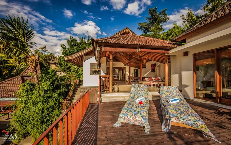 Terrasse en bois avec chaises longues devant un bâtiment à toit de chaume.