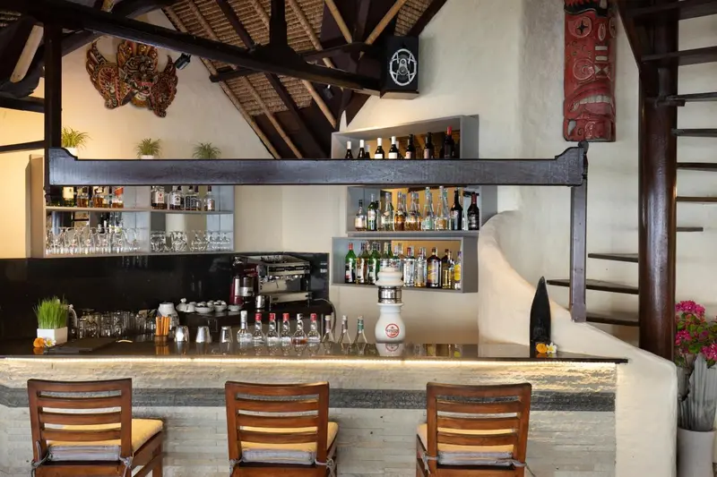 Un comptoir de bar en bois sombre présente une variété de bouteilles et de verres.