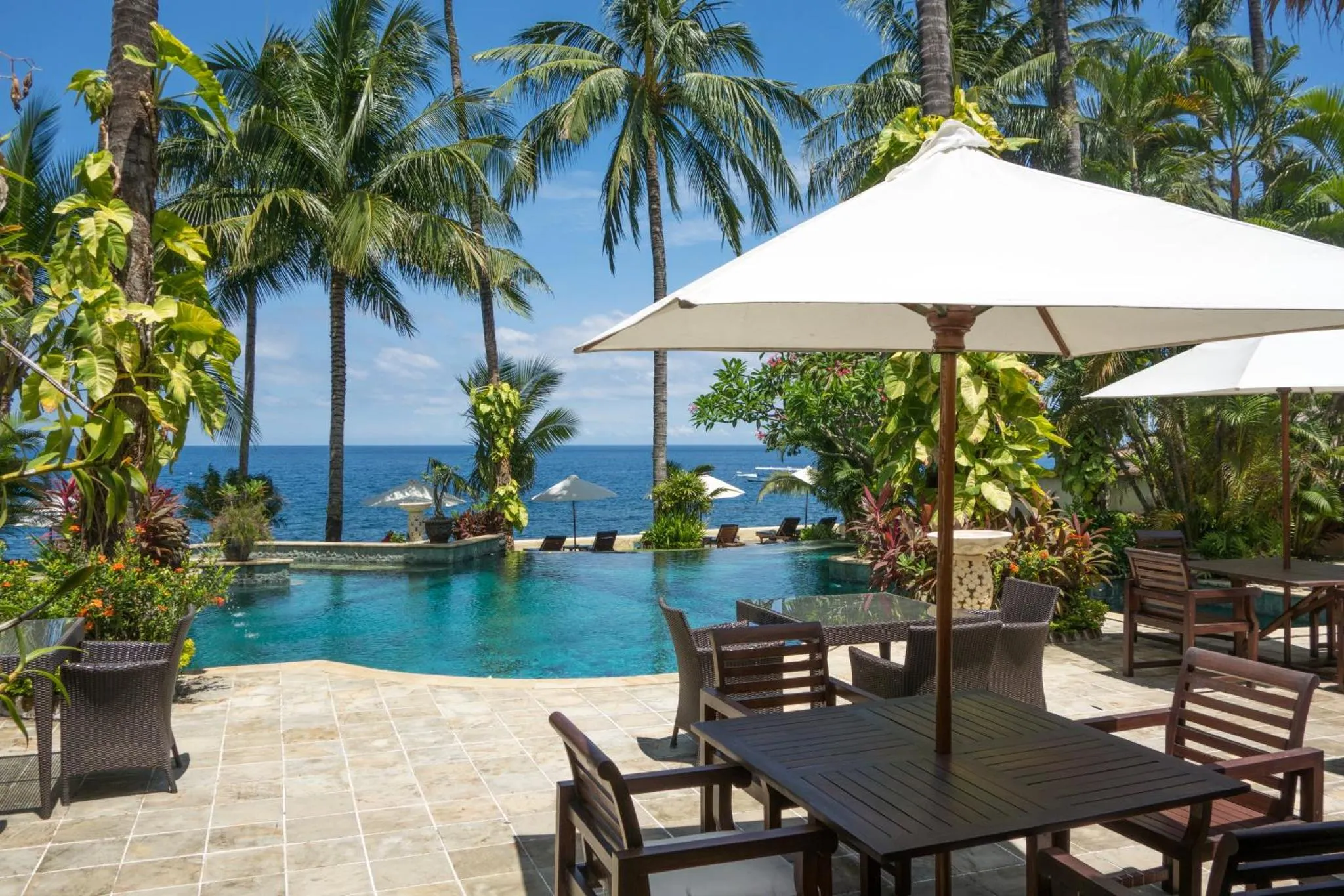 Une piscine bordée de chaises longues et de parasols, avec une vue sur la mer.