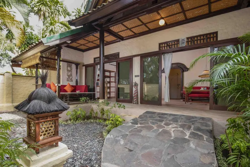 Terrasse ombragée devant une habitation avec mobilier de jardin.