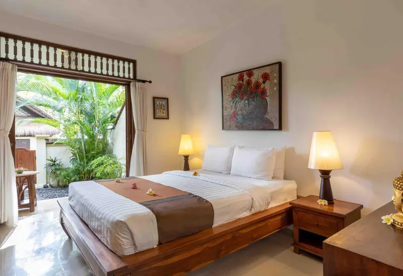 Une chambre lumineuse avec un grand lit et une vue sur une végétation luxuriante.