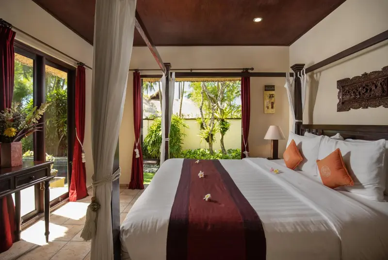 Une chambre avec un lit à baldaquin donnant sur une végétation luxuriante.
