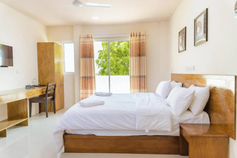 Une chambre lumineuse avec un grand lit et un bureau.