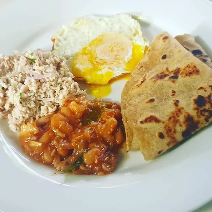 Assiette garnie d'un plat local avec oeuf au plat, riz et galettes.