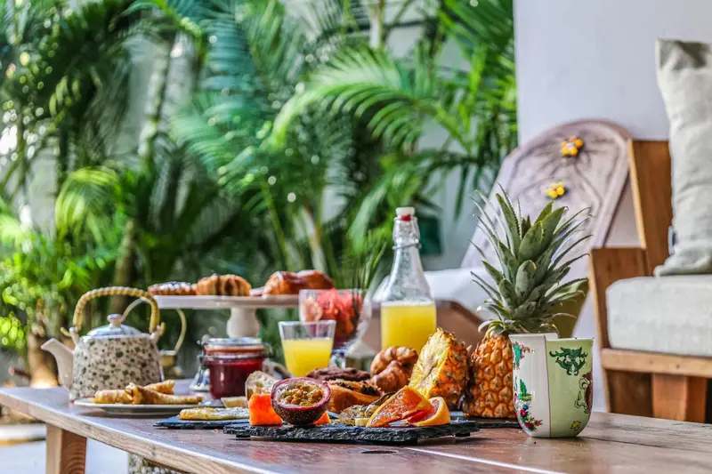 Une table en bois est dressée avec un copieux petit-déjeuner tropical.