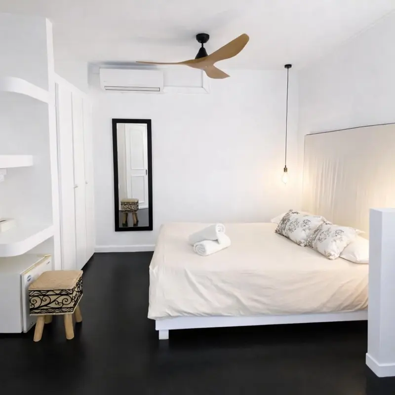 Une chambre lumineuse avec un grand lit et un miroir mural.
