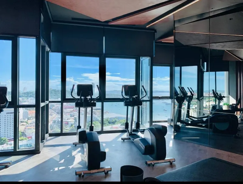Une salle de sport lumineuse offre une vue panoramique sur la mer et la ville.