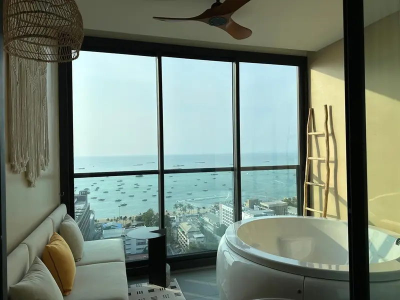 Une chambre lumineuse avec vue sur la mer et une baignoire ronde.