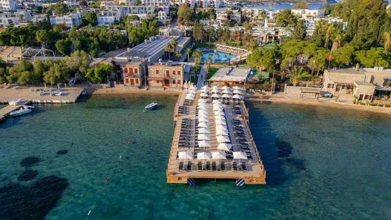 Vue aérienne d'un complexe hôtelier avec une plage et un ponton en bois.