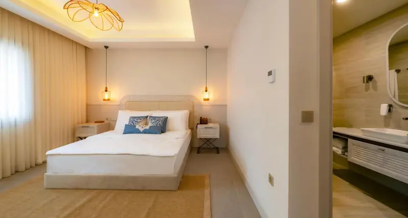 Une chambre lumineuse avec un grand lit et un espace salle de bain.