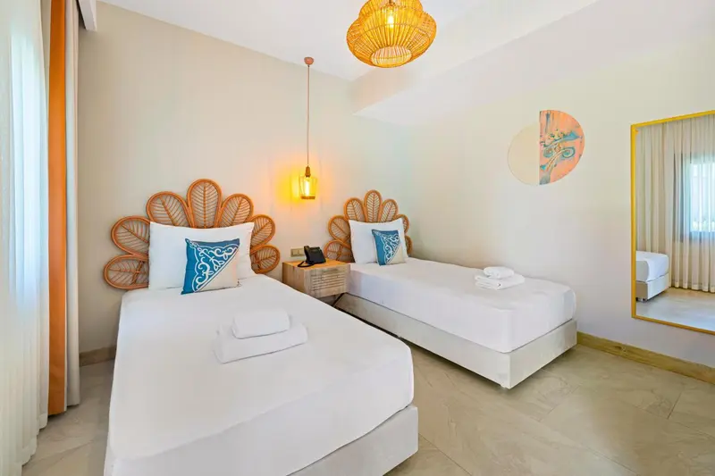 Une chambre lumineuse avec deux lits simples et une décoration murale.