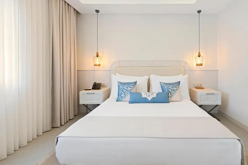 Une chambre lumineuse avec un grand lit et des tables de chevet.