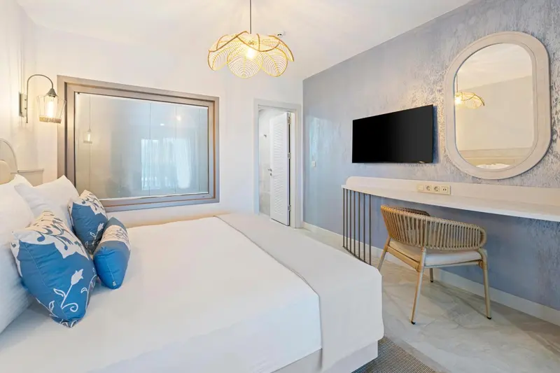 Une chambre lumineuse avec un grand lit et un bureau.