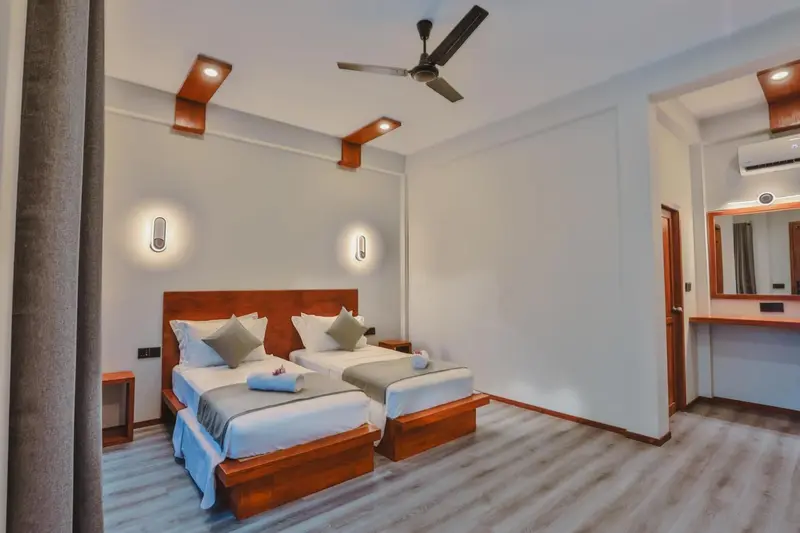 Une chambre lumineuse avec deux lits simples et un mobilier en bois.