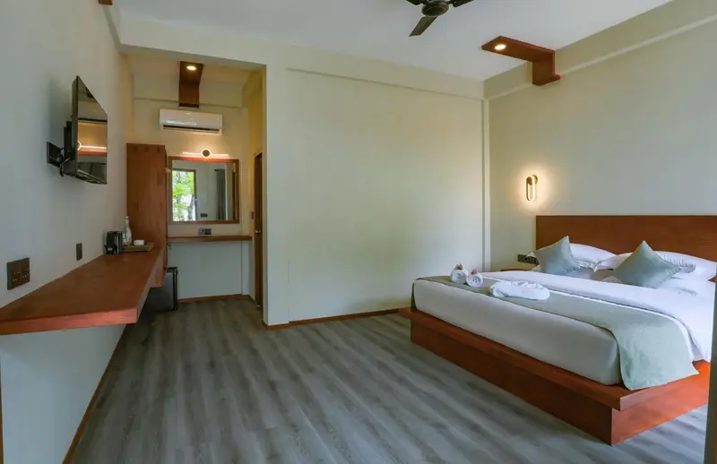 Chambre lumineuse avec un grand lit et un bureau.
