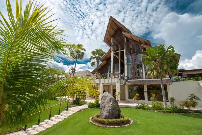 Bâtiment à l'architecture moderne entouré d'une végétation luxuriante et d'une pelouse soignée.