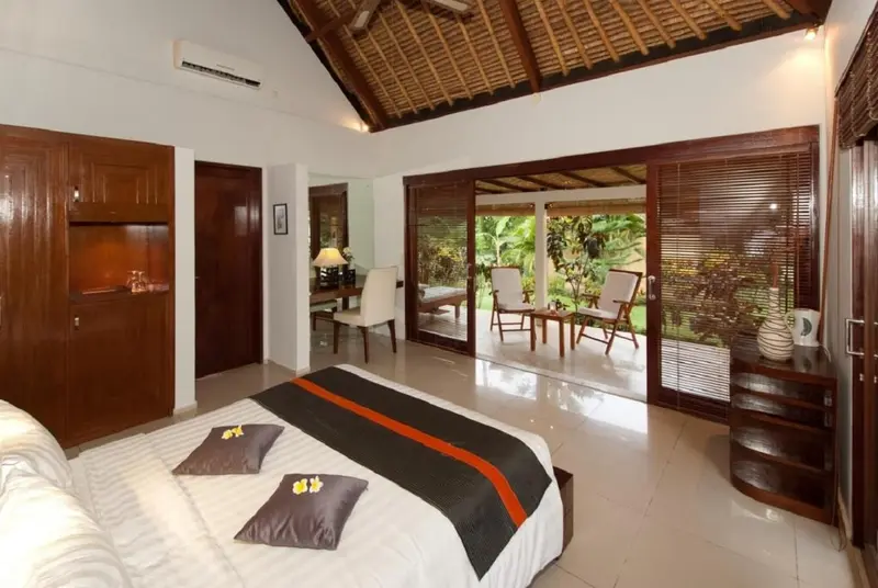 Une chambre lumineuse avec un lit recouvert d'une courtepointe décorative et un accès direct à une terrasse.