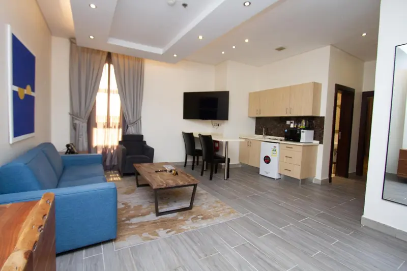 Espace de vie lumineux avec canapé, table basse et kitchenette.