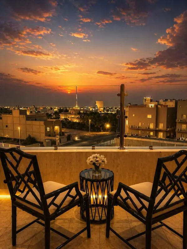 Terrasse avec mobilier d'extérieur et vue sur une ville illuminée au coucher du soleil.