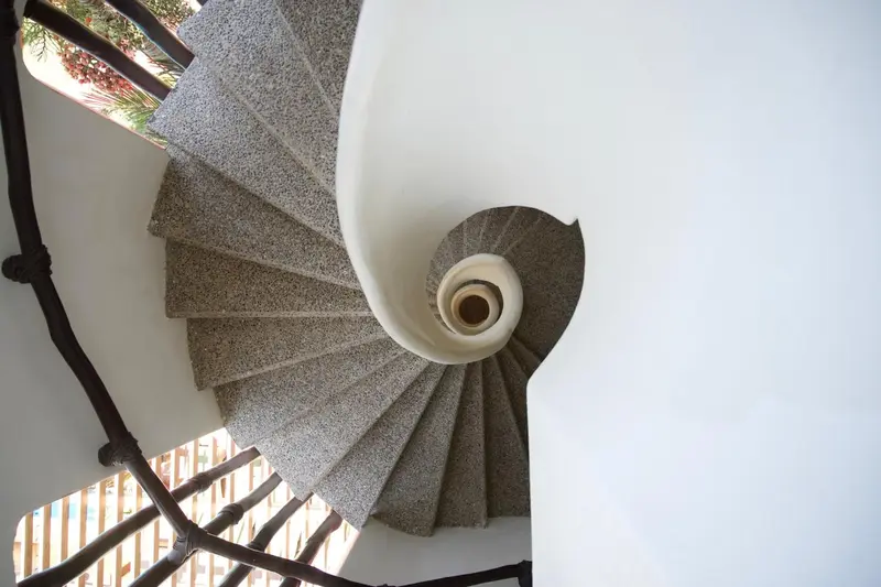 Escalier en colimaçon blanc et gris vu d'en haut.