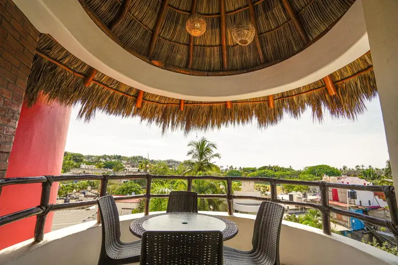 Terrasse ombragée avec mobilier de jardin et vue sur la végétation.