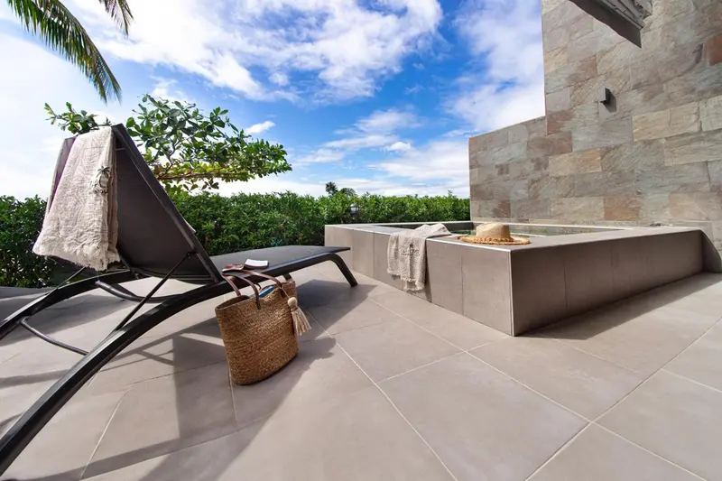 Transats et jacuzzi sur une terrasse ensoleillée.
