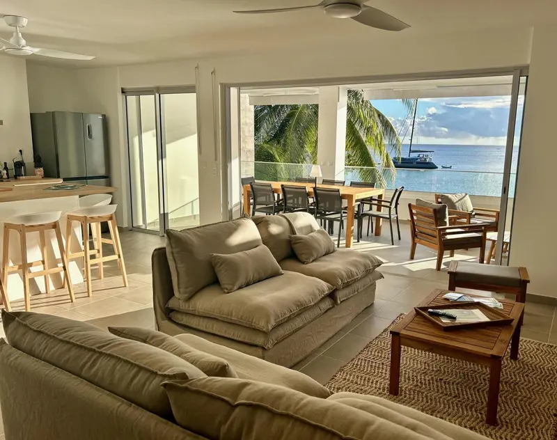 Espace de vie lumineux avec canapés confortables et vue sur la mer.