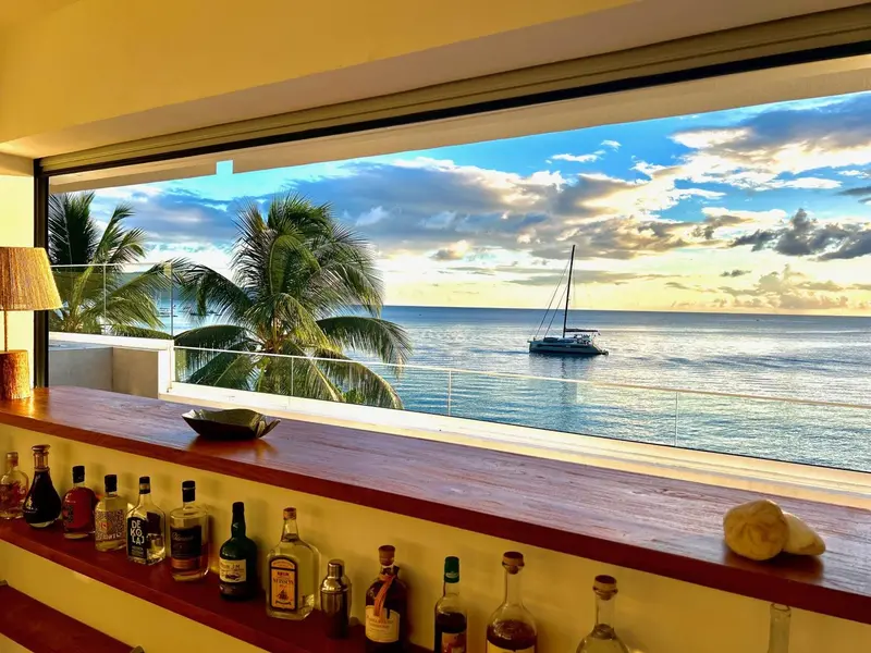 Un comptoir de bar en bois donne sur une vue maritime avec un voilier.
