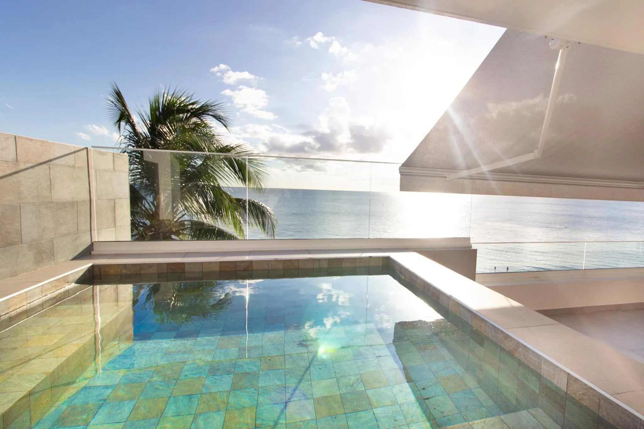 Une petite piscine turquoise sur une terrasse ensoleillée avec vue sur la mer.