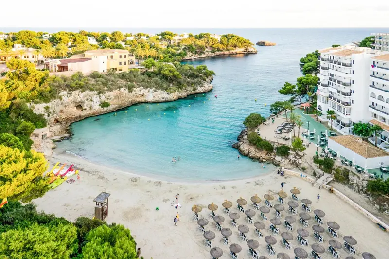 Vue aérienne d'une crique abritée avec une plage de sable et des parasols.