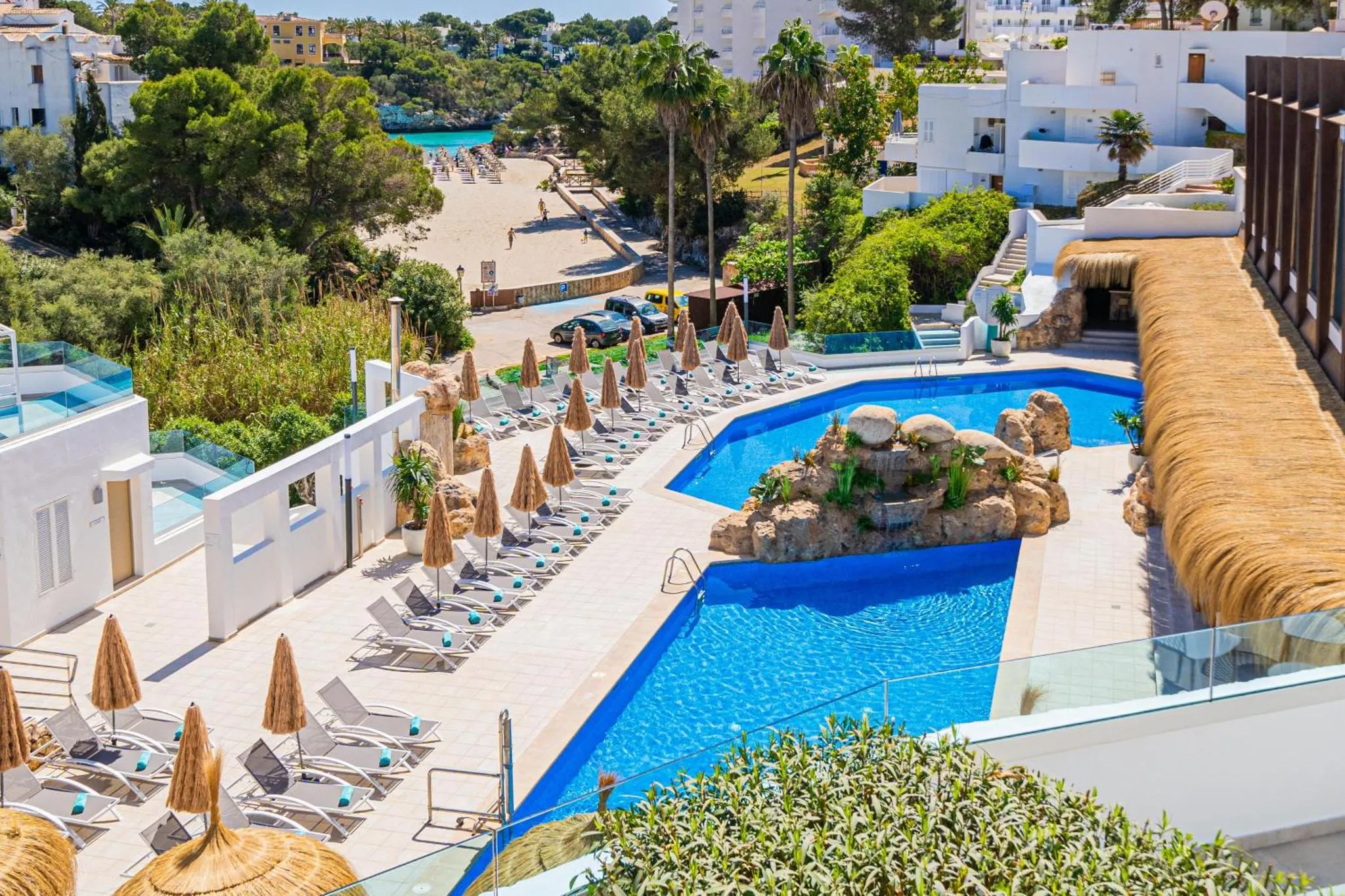 Une piscine avec des transats et des parasols offre un espace de détente en bord de mer.