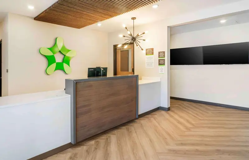 Un comptoir d'accueil moderne avec un logo vert en forme d'étoile.