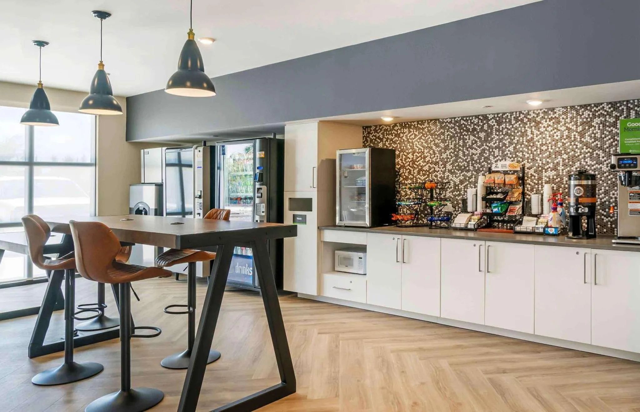 Un espace repas avec une table haute et des tabourets, près d'un comptoir de snacks et de boissons.