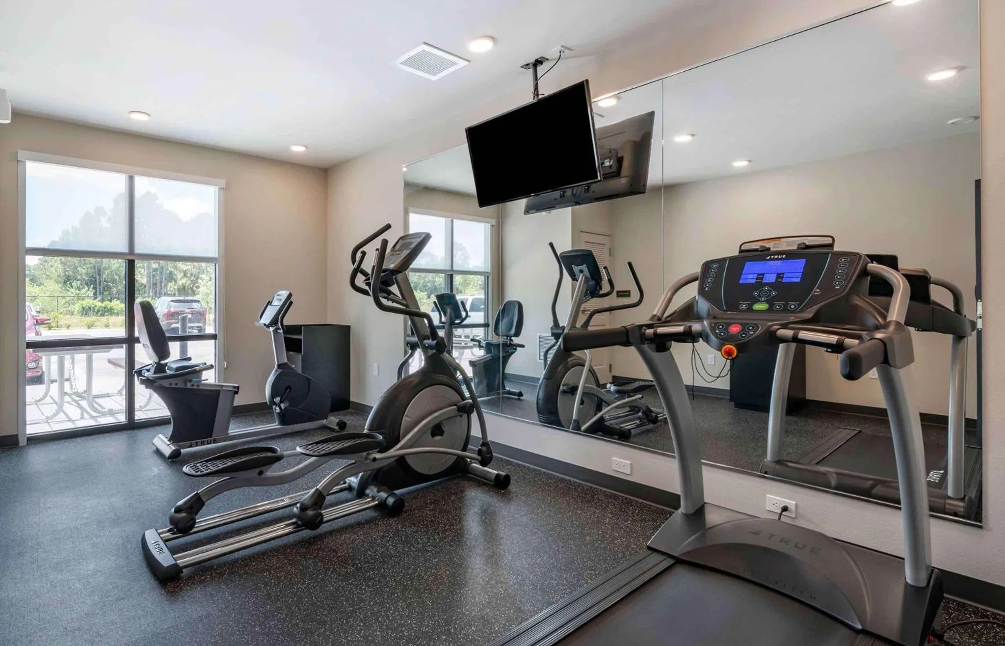 Une salle de sport avec des équipements de fitness et un grand miroir.