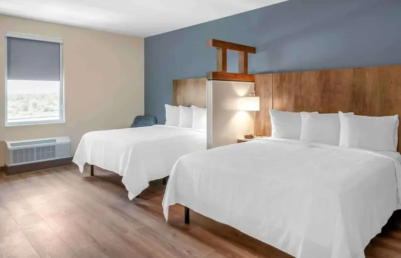 Chambre avec deux lits doubles et une fenêtre.