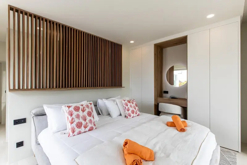 Un lit recouvert d'une couette blanche et de coussins decoratifs dans une chambre lumineuse.