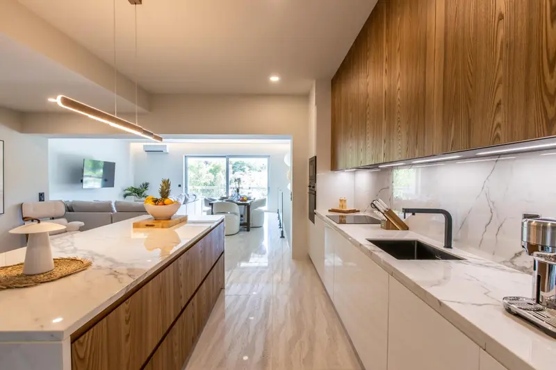 Cuisine moderne et lumineuse avec un îlot central et un espace salon ouvert.