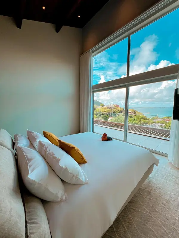 Une chambre lumineuse avec un grand lit donnant sur une vue mer.