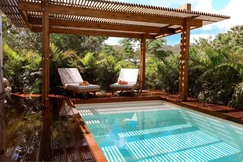 Deux transats invitent à la détente au bord d'une piscine rectangulaire dans un cadre tropical.