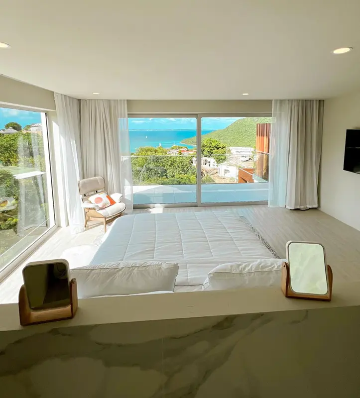 Une chambre lumineuse avec un grand lit donnant sur une vue sur la mer.
