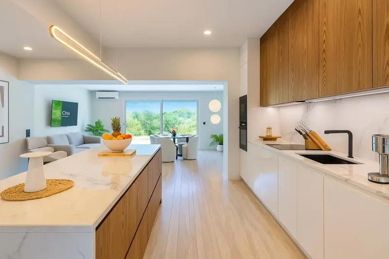 Une cuisine moderne et lumineuse s'ouvre sur un espace de vie avec vue sur la végétation.