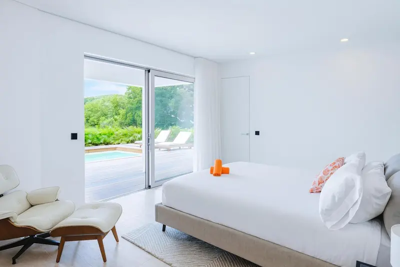 Une chambre lumineuse avec un grand lit et un accès à une terrasse avec piscine.